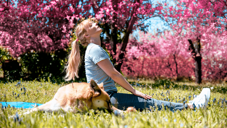 woman reducing her stress and back pain relief in a park with her dog after seeing an Orpington Chiropractor